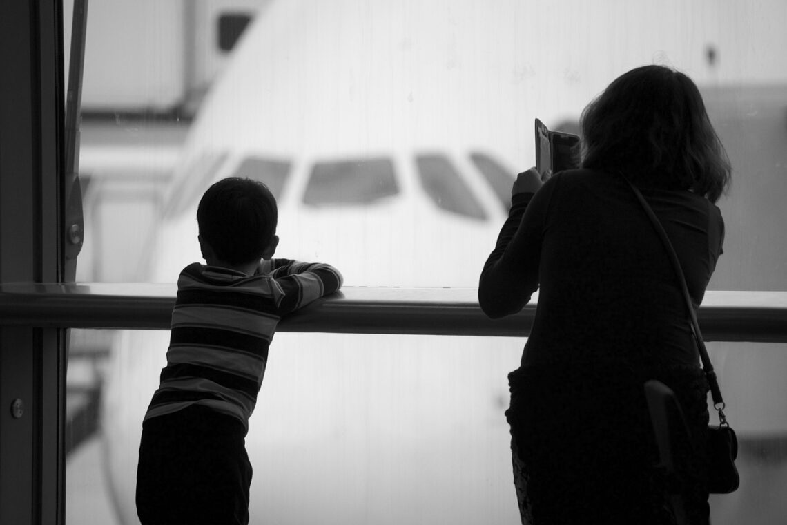 Child and mom looking out the window at a plane